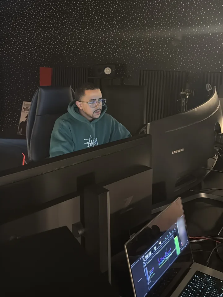 Ismail Tazzit au montage, derrière ses écrans, un ordinateur portable ouvert sur Premiere Pro.